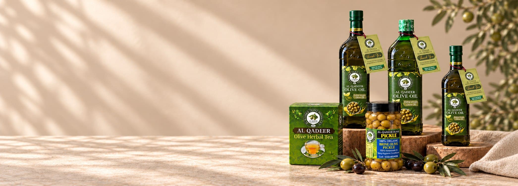 Al-Qadeer olive oil bottles, brine olive pickle and olive herbal tea on a sunlit table
